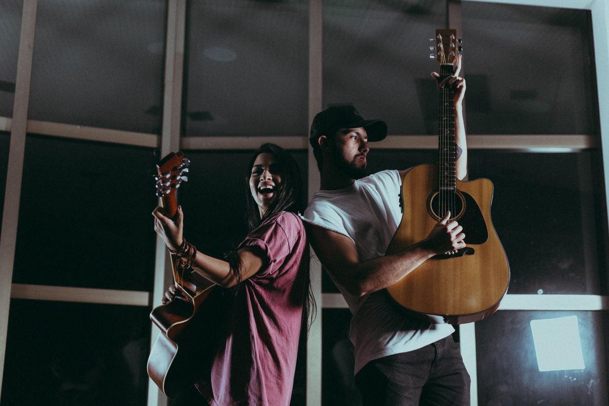 Two musicians playing acoustic guitars together at night