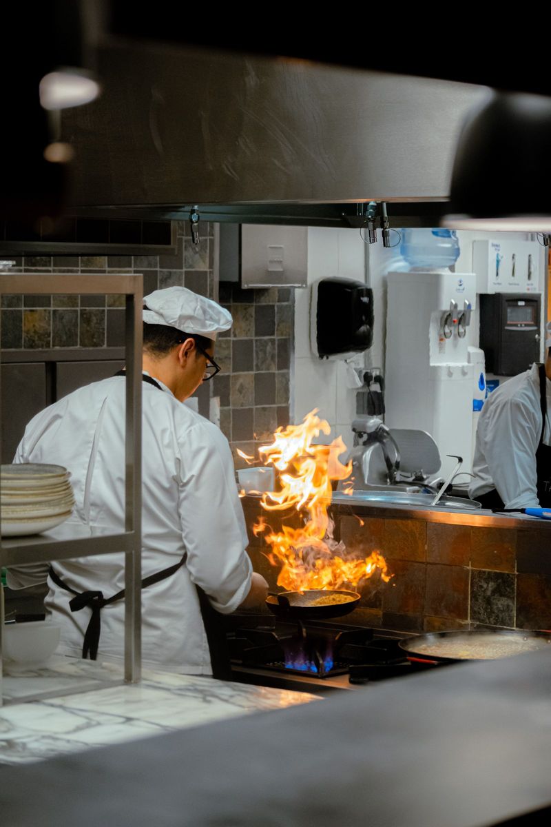 A chef working a flaming pan on the line