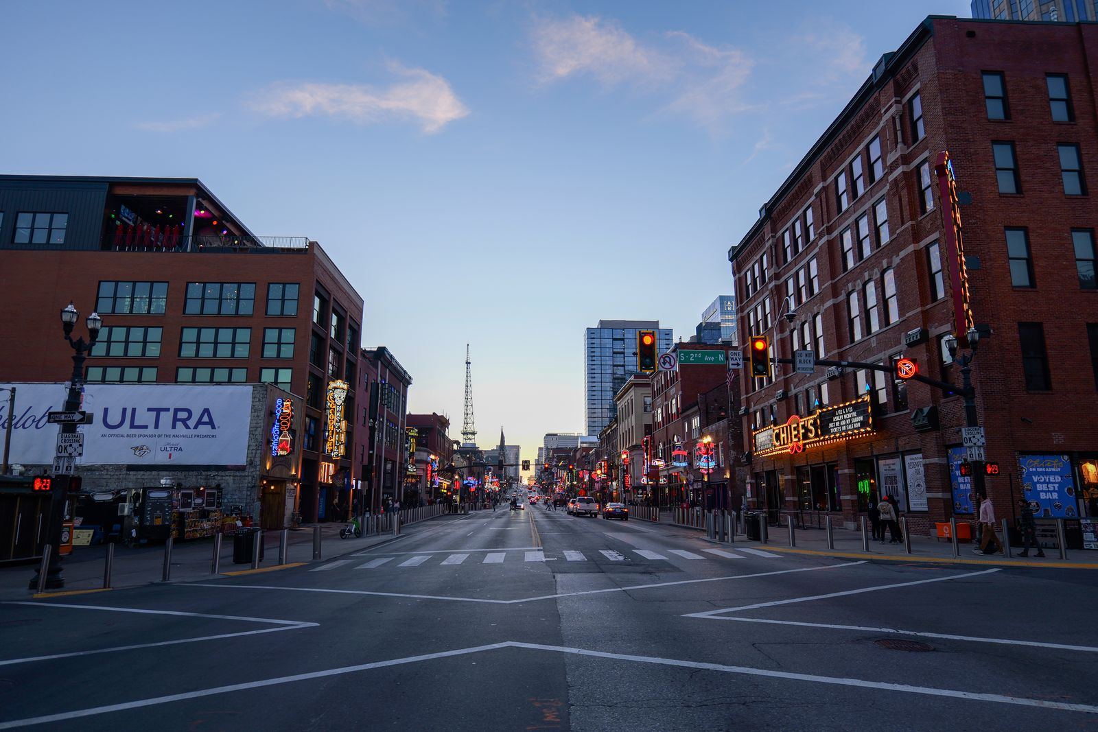 Lower Broadway in Nashville at dusk, neon signs and honky tonks along the street