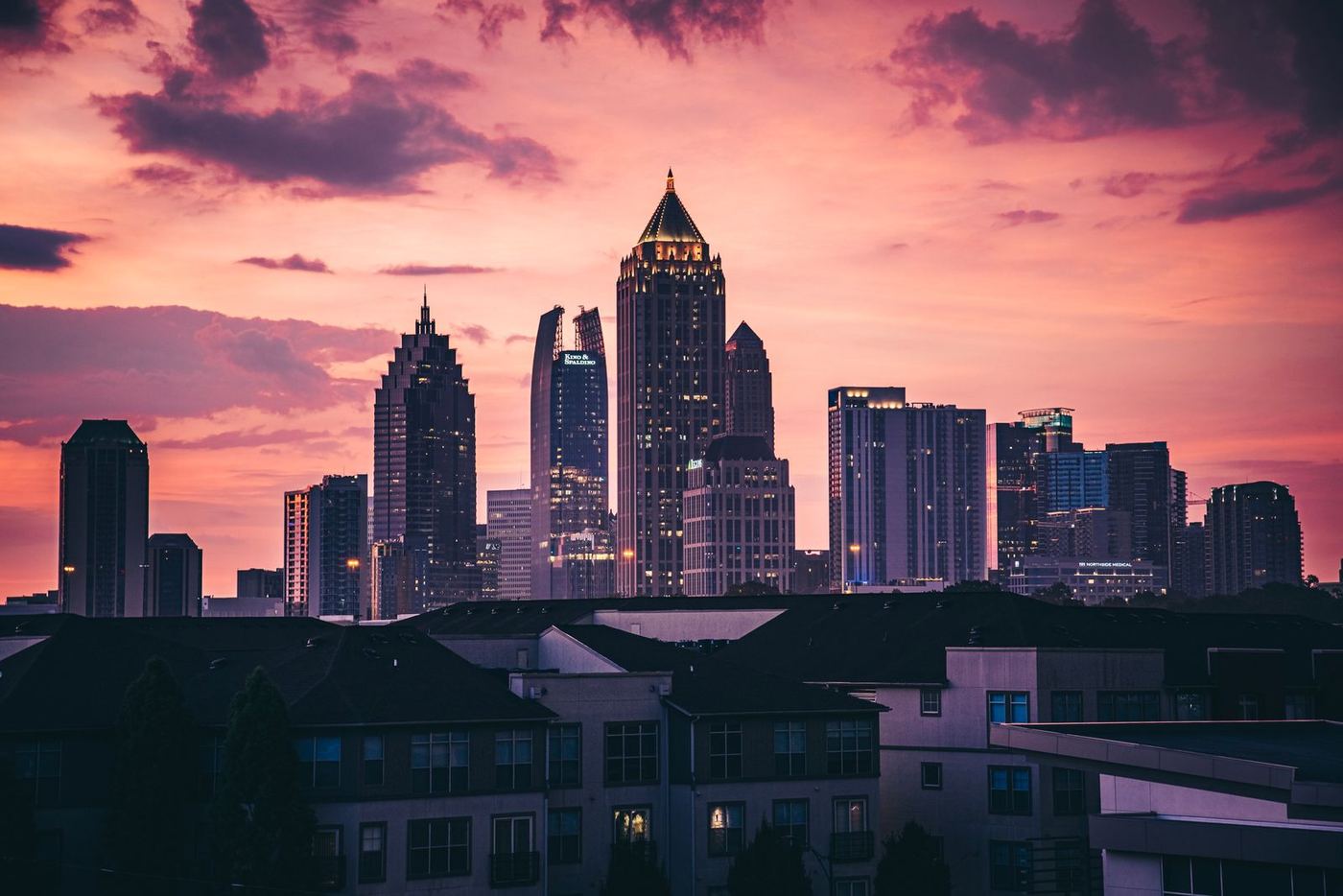 The Midtown Atlanta skyline at sunset, seen over neighborhood rooftops
