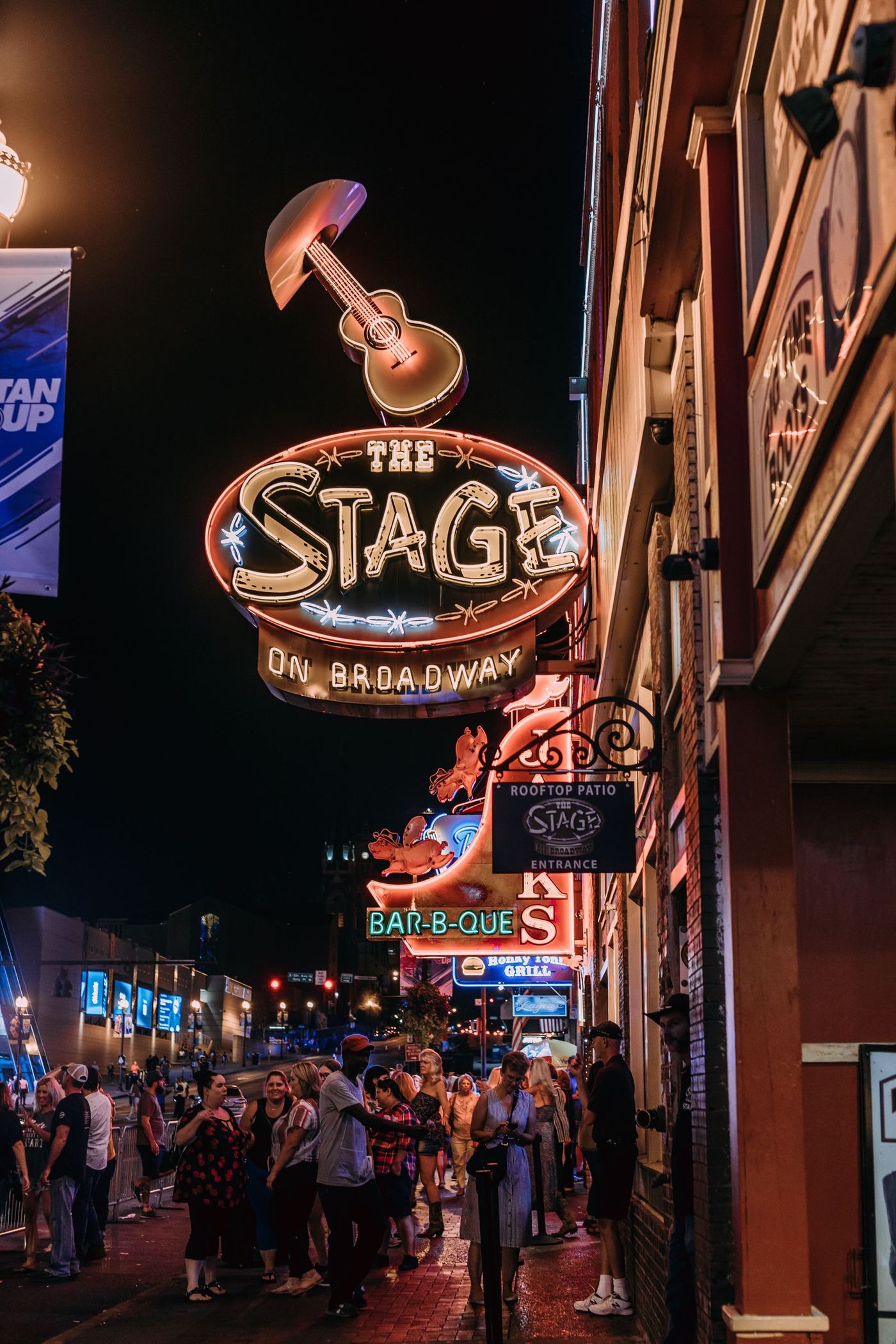 The Stage on Broadway neon sign above a nighttime crowd on Lower Broadway, Nashville