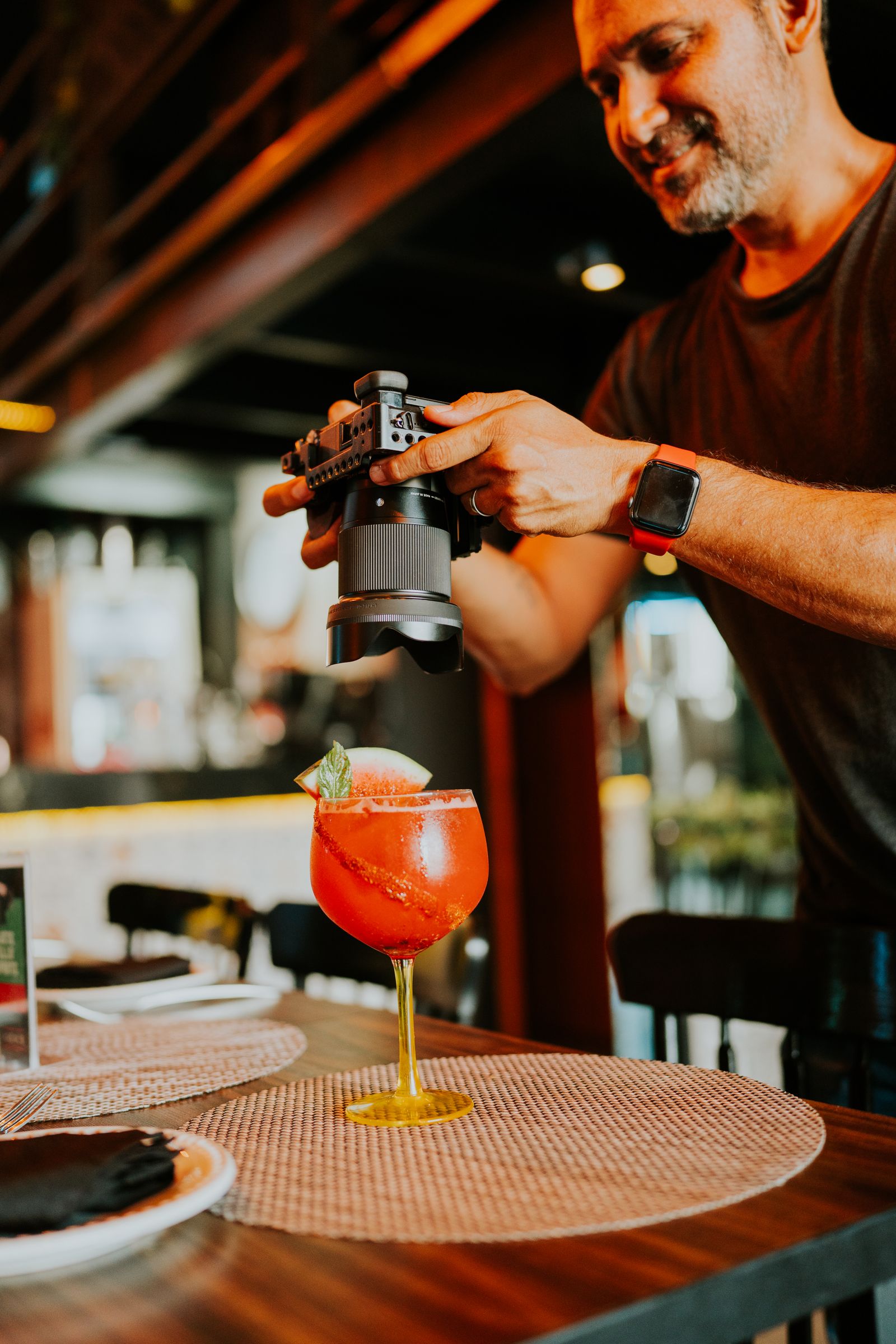 A local creator photographing a cocktail at a bar table