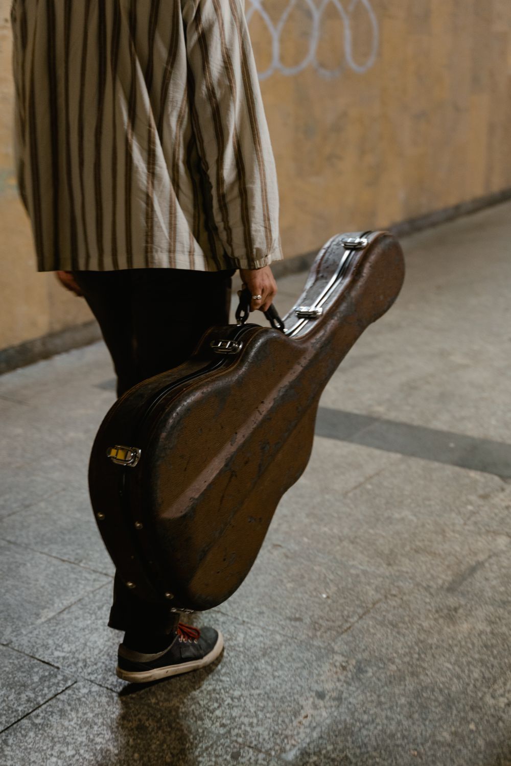A musician carrying a guitar case down the street