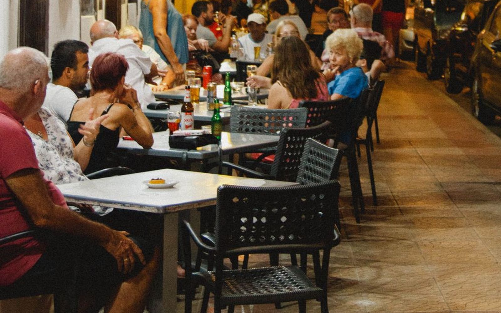 Diners at sidewalk tables on a warm night