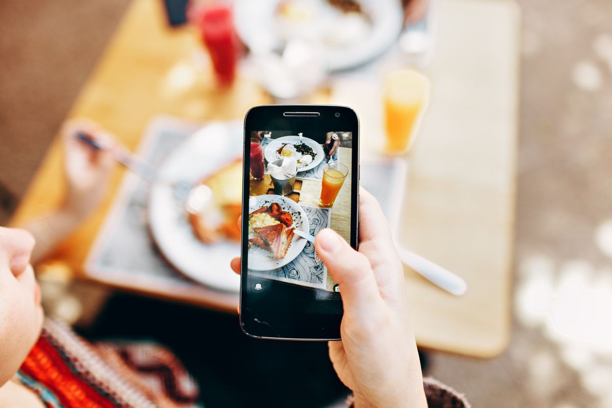 A creator photographing a meal at a local business table